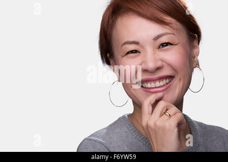 Un colpo di testa di un sorridente di mezza età donna giapponese su uno sfondo bianco. Foto Stock