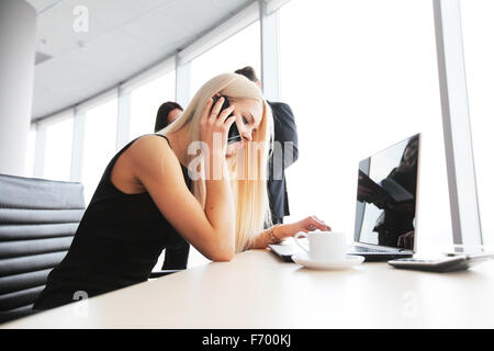 Giovane imprenditrice carino parlando al telefono in ufficio Foto Stock