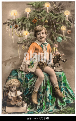 Felice ragazzo con albero di natale, regali e giocattoli d'epoca. Antique Picture con pellicola originale di granella e graffi Foto Stock