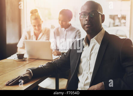 Nero rilassato business man in ufficio, persone in background Foto Stock