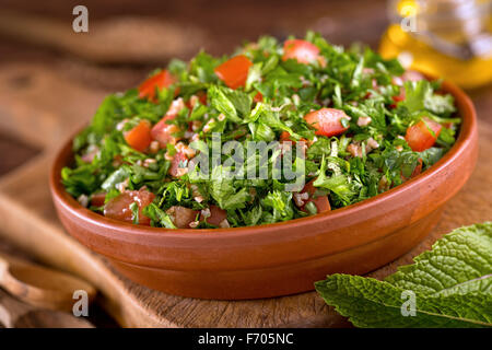Una ciotola di freschi e deliziosi tabouli con prezzemolo, menta, pomodoro, cipolla, olio d'oliva, il succo di limone e bulgar grano. Foto Stock