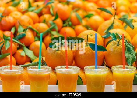 Succo di arancia frullati di frutta di fronte ad un mucchio di arance fresche Foto Stock