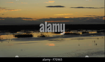 Orange sky twilight spiaggia vista attraverso saltmarsh con riflessi grigio verso il cloud bank su Ribble Estuary, Fairhaven, Lytham Foto Stock