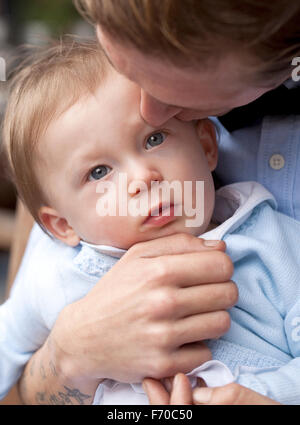 Dolce bacio. Un giovane bambino viene dolcemente baciata dal suo padre. Il suo padre è trattenere il bambino teneramente. Foto Stock