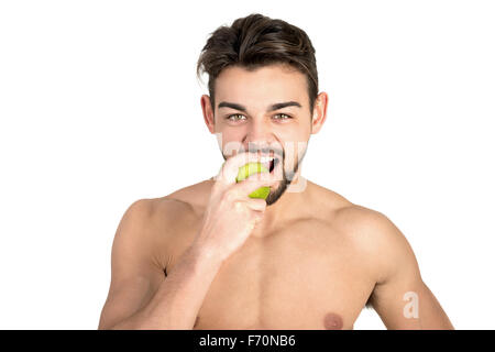 Bello e montare il giovane uomo mangiare un apple isolato in bianco Foto Stock