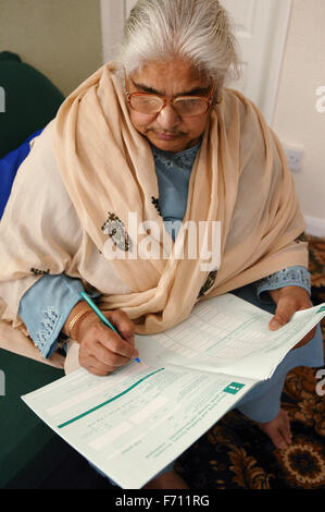 South Asian lady compilando un modulo, Foto Stock