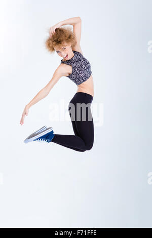 A piena lunghezza Ritratto di una giovane donna entusiasta jumping isolato su uno sfondo bianco Foto Stock