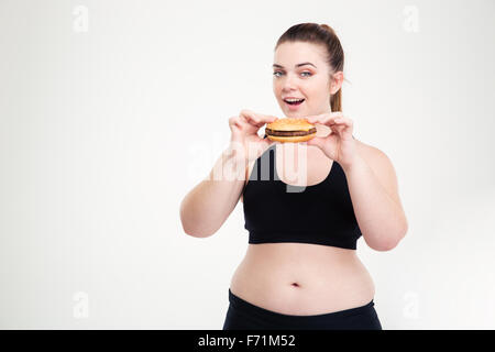 Ritratto di una donna spesso mangiare hamburger isolato su uno sfondo bianco Foto Stock