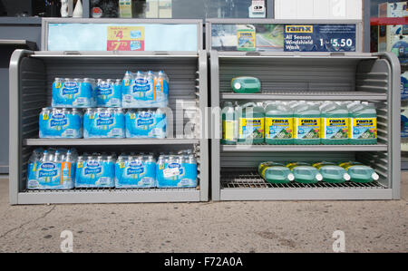 Acqua in bottiglia pacchi avvolti in plastica e il liquido lavavetri parabrezza in vendita presso la stazione di gas. Foto Stock