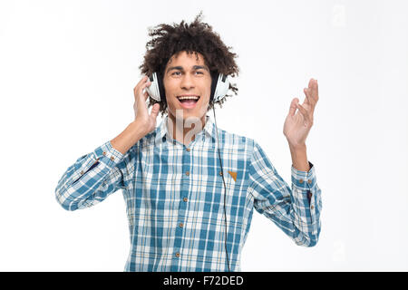 Ritratto di Allegro afro american uomo con capelli ricci ascoltando la musica nelle cuffie isolato su uno sfondo bianco Foto Stock