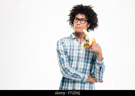 Ritratto di un ragionato afro-americano tenendo banana isolato su uno sfondo bianco Foto Stock