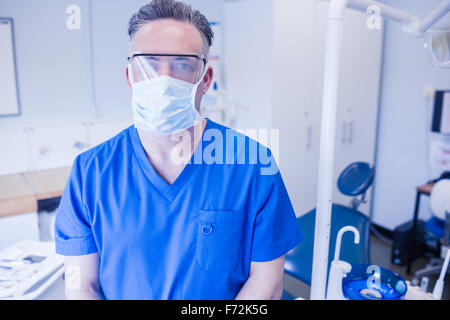 Dentista indossando maschera chirurgica e occhiali di sicurezza Foto Stock