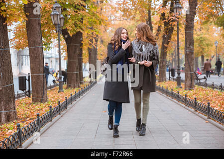 Ritratto di due amiche camminare e parlare in autunno park Foto Stock