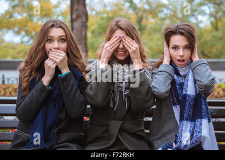 Ritratto di tre donne in panchina e che rappresentano i sensi: mute, ciechi e sordi all'aperto Foto Stock