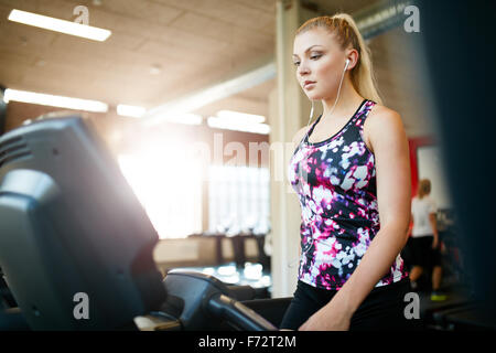 Scatto di una donna che cammina sul tapis roulant in palestra. Giovane femmina focalizzato esercitare presso un club salute, formazione su attrezzature ginniche. Foto Stock