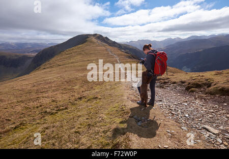 Un escursionista controllo posizione GPS sul bordo Hindscarth con Dale in testa la distanza, Lake District inglese, UK. Foto Stock