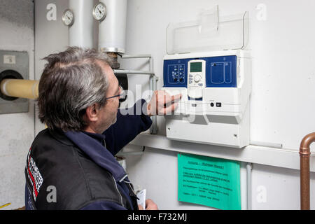 Custode controlla il sistema di riscaldamento nella sala caldaie Foto Stock