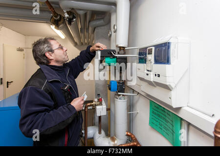 Custode controlla il sistema di riscaldamento nella sala caldaie Foto Stock