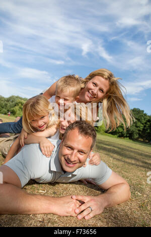 Famiglia con tre bambini che giocano in un parco. Foto Stock