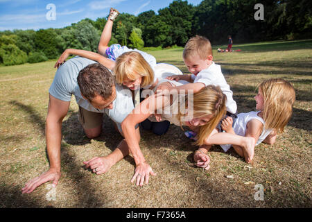 Famiglia con tre bambini che giocano in un parco. Foto Stock