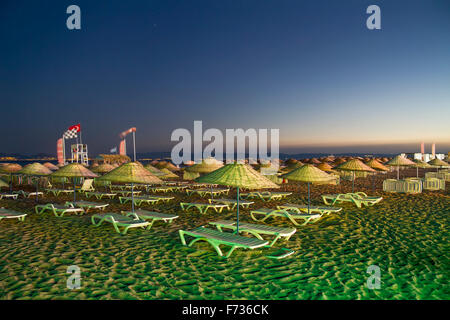 Lettini e ombrelloni di paglia sulla spiaggia di Sarimsakli, la Turchia di notte Foto Stock