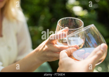 In prossimità di due persone azienda bicchieri con vino rosato, di tostatura a vicenda. Celebrazione. Foto Stock