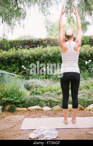 Donna bionda fare yoga in un giardino. Foto Stock