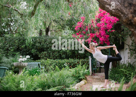 Donna bionda fare yoga in un giardino. Foto Stock