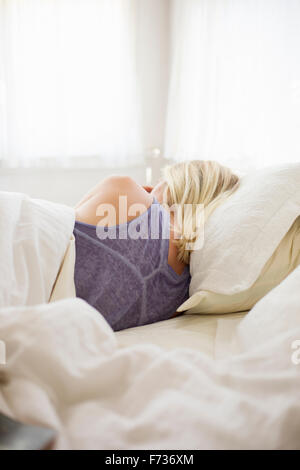 Donna bionda che dormono in un letto con biancheria bianca. Foto Stock