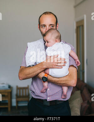 Un uomo con un bambino piccolo vicino al suo petto. Foto Stock