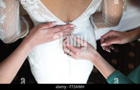 Sposa mettendo sul suo vestito Foto Stock