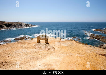 Un banco di pietra di fronte all'Oceano Atlantico, Porto Covo, Alentejo, Portogallo. Foto Stock
