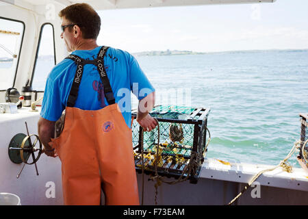 Lobster Boat captain sterzo e circa al posto di una trappola di aragosta Foto Stock