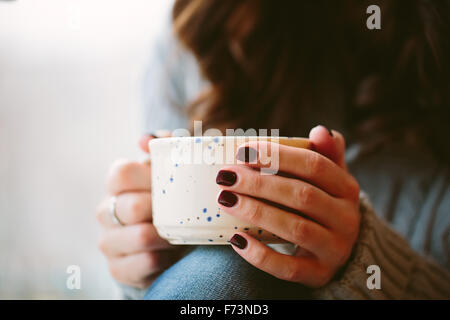 Giovane donna mani tenendo una tazza. Foto Stock