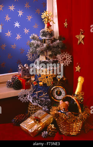 Festive Capodanno Natale ancora vita decorativa con un abete, regali di Natale e ore in formato verticale. sfondo rosso. Foto Stock