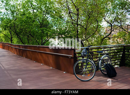 Bicicletta appoggiata contro un recinto con alberi.uno stile di vita urbano Foto Stock