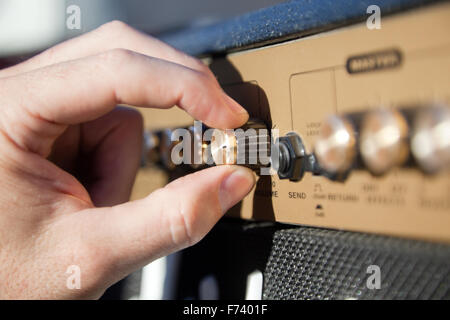 Stretta di mano il controllo del volume di un amplificatore Foto Stock