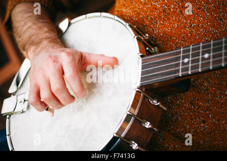 Close up di un maschio lettore Banjo rilassante sotto il portico, praticanti e di presa di distanza Foto Stock