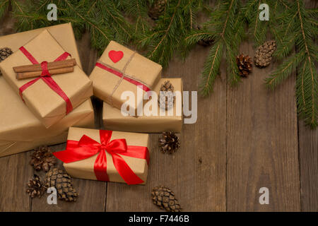 Composizione di natale con presenta un nastro rosso, abete e pino coni scuri sullo sfondo di legno in stile vintage con copyspa Foto Stock