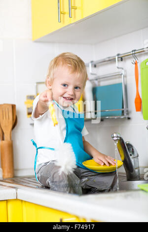 Felice toddler boy lavando i piatti in cucina Foto Stock