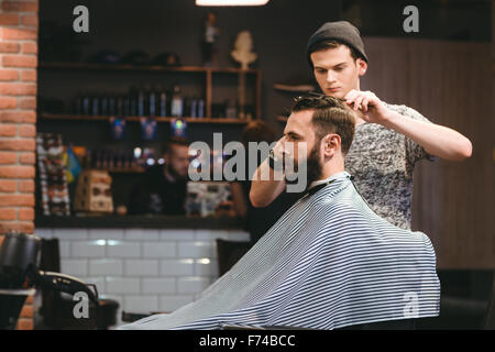 attraente barbiere che fa taglio di capelli di bell'uomo in barbiere,  accessori per capelli Foto stock - Alamy