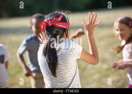 I bambini divertendosi cieco il buff al parco Foto Stock