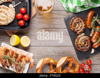 Boccale di birra, i gamberi alla griglia, salsicce e pretzel su un tavolo di legno. Vista da sopra con lo spazio di copia Foto Stock