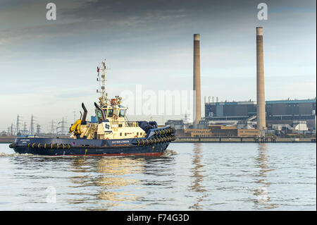 Il rimorchiatore, Svitzer Londra, passa Tilbury B power station in Essex come si cuoce a vapore downriver sul Fiume Tamigi. Foto Stock