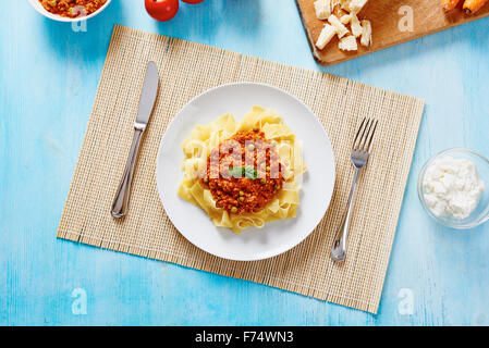 Tagliatelle al ragù sulla piastra bianca e blu tavolo in legno Foto Stock