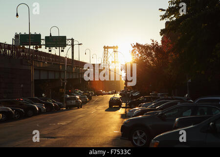 Visualizza in basso un Lower East Side backstreet dal Williamsburg Bridge come il sole sorge e razzi nella lente della fotocamera Foto Stock