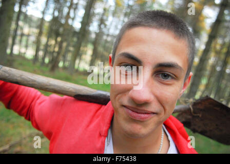 Ragazzo adolescente con la pala a scavare nella foresta. Foto Stock