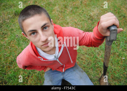 Ragazzo adolescente con la pala a scavare nella foresta. Foto Stock