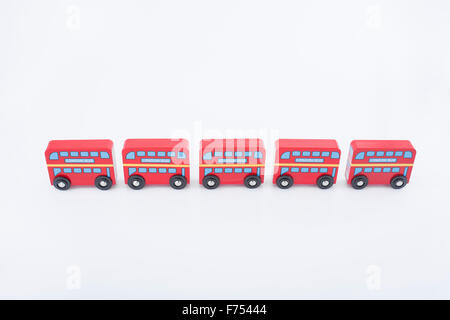Dipinto di giocattoli di legno di Londra autobus su uno sfondo bianco. Metafora per andare in giro per Londra, lavorando a Londra e London il pendolarismo. Foto Stock
