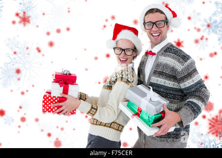 Immagine composita del ritratto di Felice l uomo e la donna che indossa cappelli di Babbo Natale e regali di contenimento Foto Stock